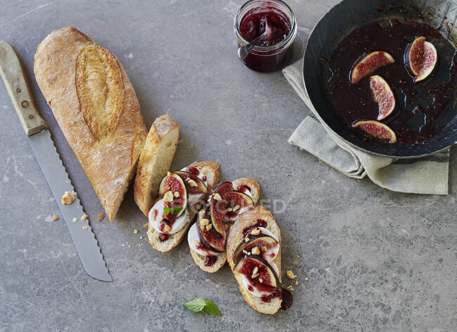 Sliced baguette topped with figs, goat's cheese and jam — Stock Photo