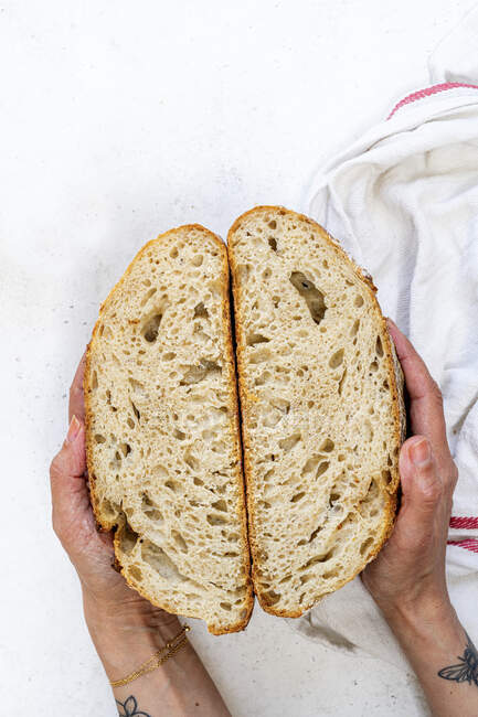 Mãos segurando metades de pão Sourdough — Fotografia de Stock