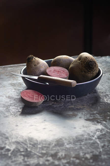 Beetroot, whole and halved, in a bowl with a knife — Stock Photo
