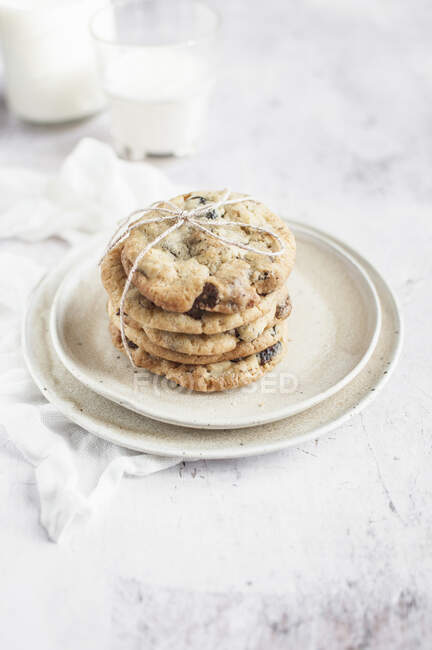 Plates with chocolate chips cookies with raisins and milk — Stock Photo