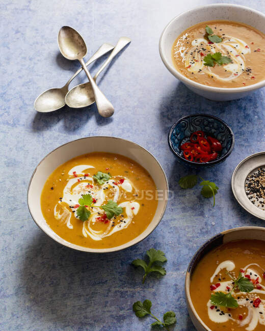 Carrot soup with coconut milk, red chilies, cilantro, white and black sesame seeds — Stock Photo