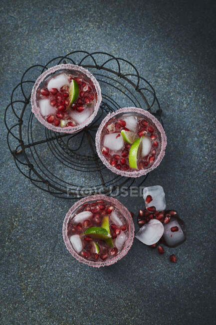 Gim e Tonic com sementes de romã em copos com bordas açucaradas, gelo e limas — Fotografia de Stock
