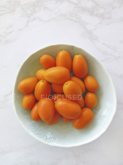 Mandarinas frescas maduras en un tazón sobre un fondo blanco. - foto de stock