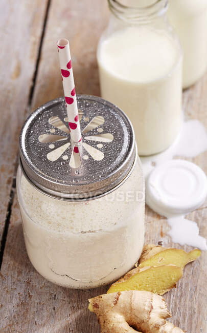 Una lassi de plátano y jengibre en un frasco con tapa de rosca con yogur, lima y especias - foto de stock