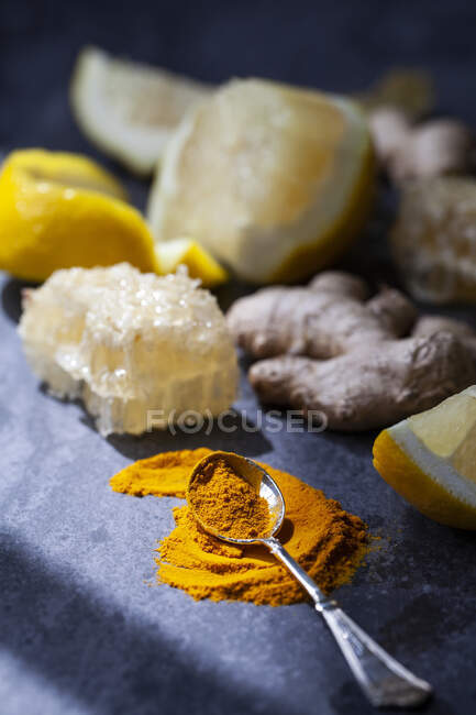 Citron, poudre de curcuma, gingembre et nid d'abeille sur une surface bleue — Photo de stock