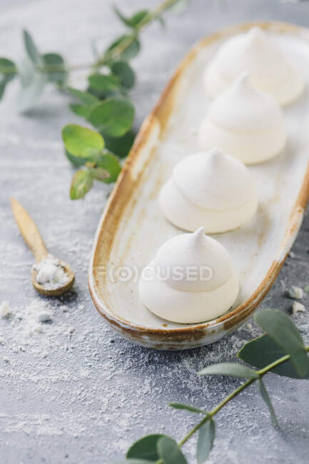 Meringhe bianche su piatto lungo con foglie verdi e cucchiaio — Foto stock