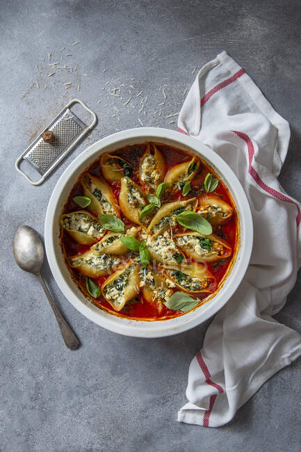 Conchiglioni pasta filled with ricotta cheese, nutmeg and spinach with tomato and basill sauce — Stock Photo