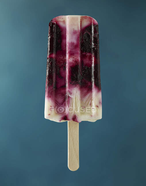 Um picolé de iogurte de mirtilo contra um fundo azul — Fotografia de Stock