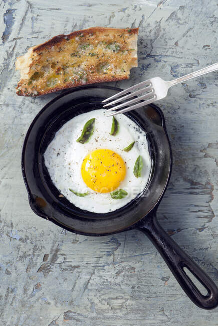 Смажене органічне яйце в міні-каструлі зі свіжим базиліком і шалотним хлібом — стокове фото
