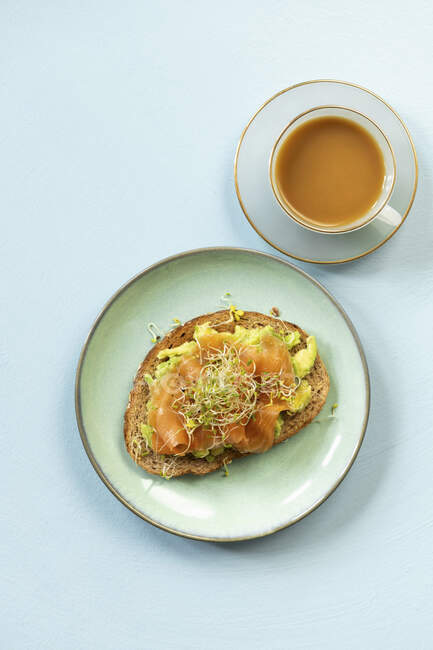 Fatias de pão cobertas com abacate e salmão defumado para o pequeno-almoço — Fotografia de Stock