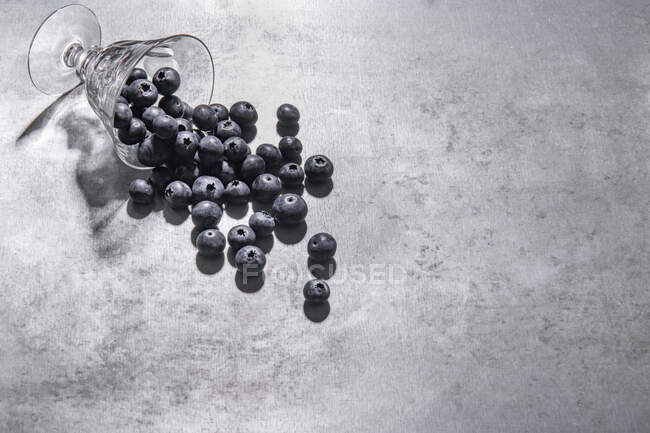 Blaubeeren aus Glas auf Steinoberfläche verschüttet — Stockfoto