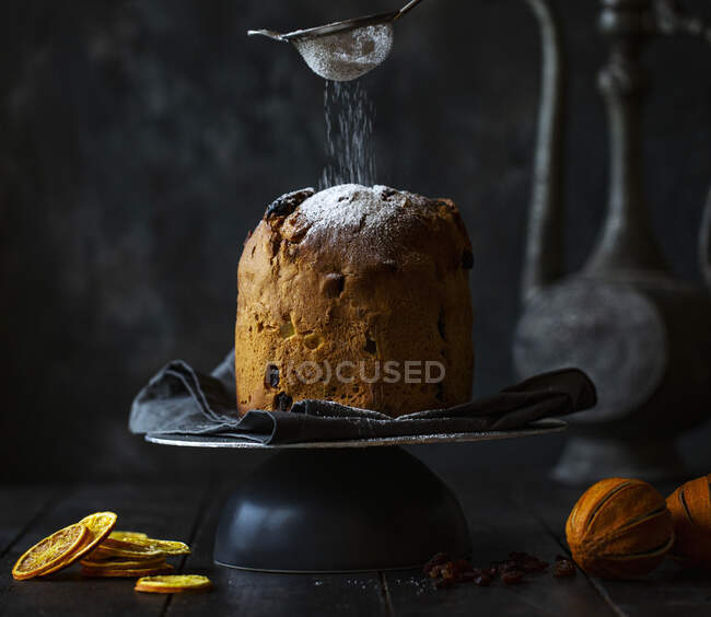 Panettone with icing sugar being dusted on to it — Stock Photo
