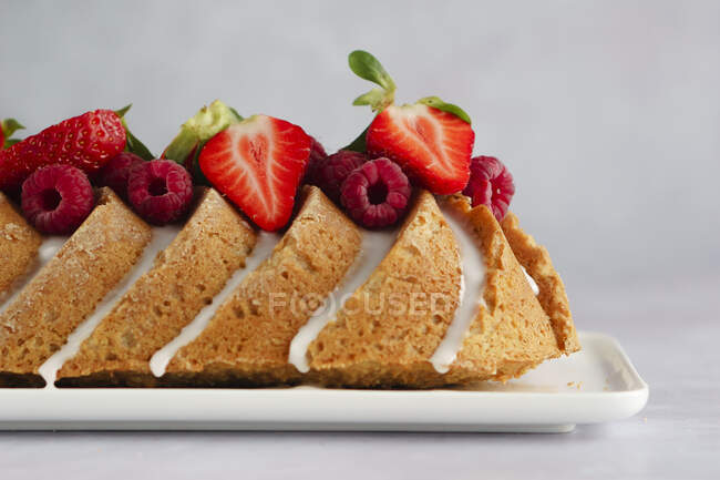 Summery coconut cake with icing, raspberries and strawberries — Stock Photo