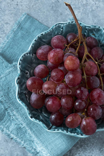 Uvas vermelhas na videira em tigela com pano azul — Fotografia de Stock