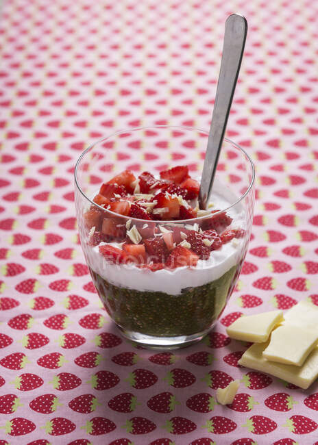 Budín de chía Matcha con crema de chocolate con leche de arroz blanco y fresas frescas en vaso con cuchara - foto de stock