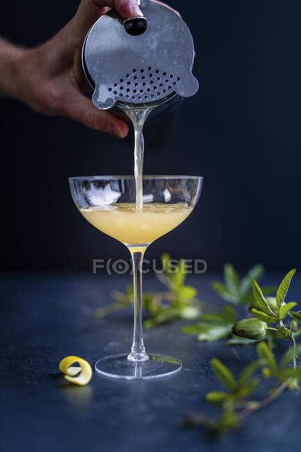 Bartender pouring cocktail in glass with lemon and mint — Stock Photo