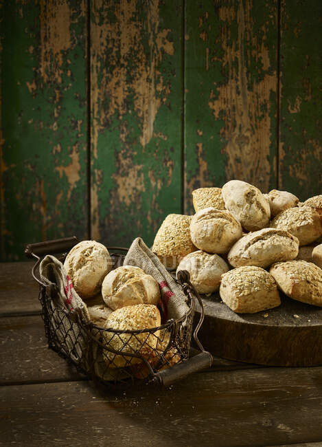 Rollos artesanales en una cesta de pan y al lado de ella - foto de stock