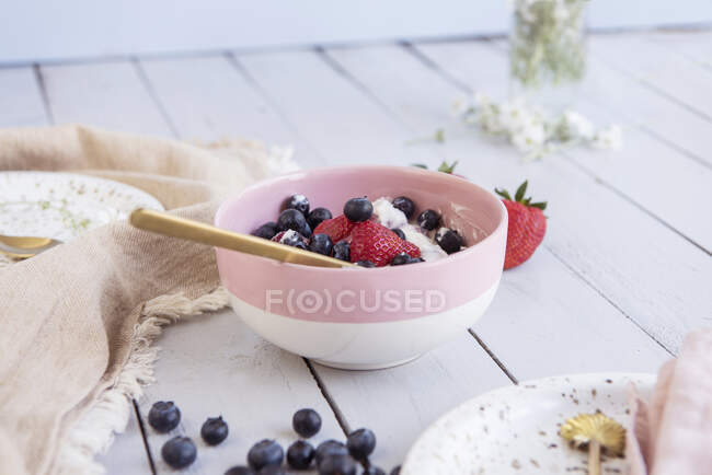 Йогурт с различными ягодами в розовой миске — стоковое фото