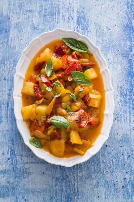 Stewed Bell peppers and potatoes served with basil leaves — Stock Photo