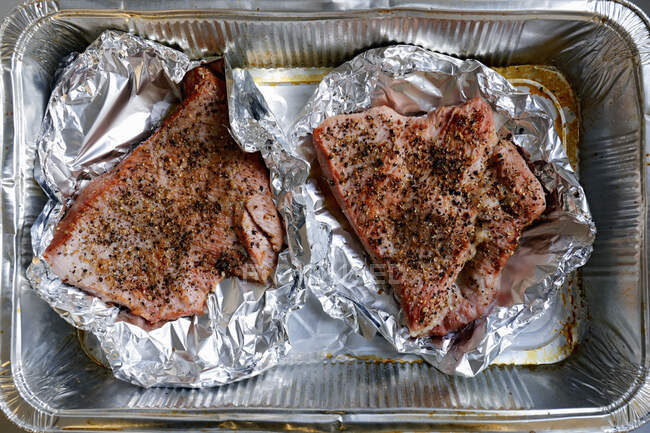 Pastrami with spices on aluminum foil in tin — Stock Photo