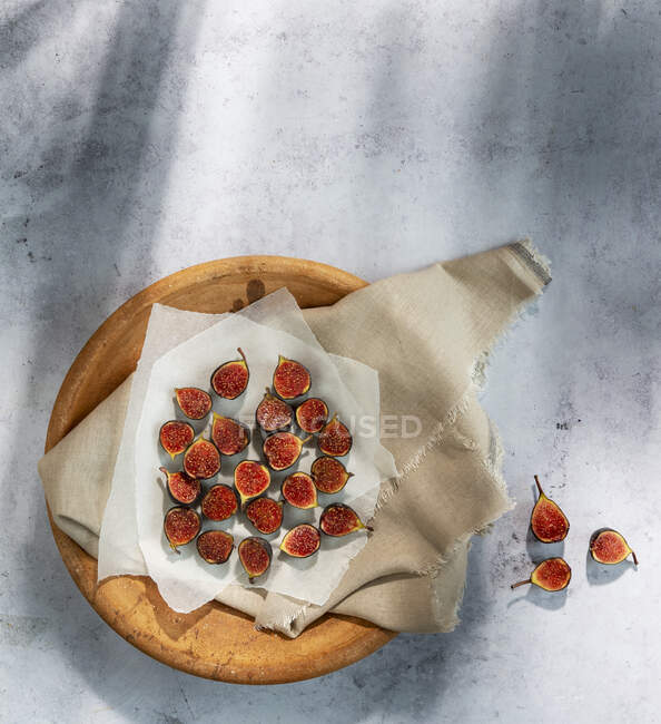 Small Fresh Figs cut in halves on paper and wooden board — Stock Photo