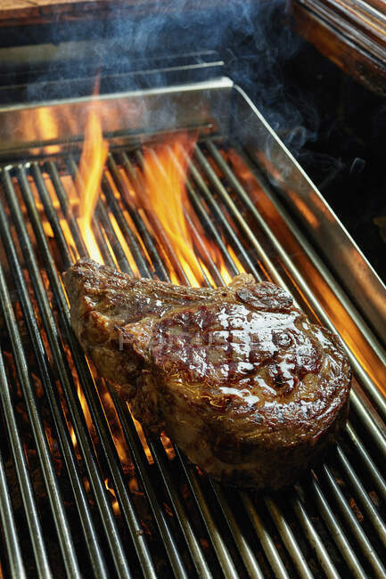 Bistecca di Ribeye su una griglia fiammeggiante — Foto stock