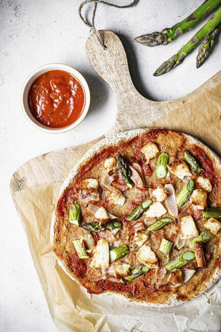 Glutenfreie Sauerteigpizza mit Spargel-Halloumi-Speck und Tomatensauce — Stockfoto