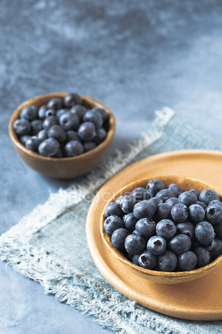 Blueberries in wooden bowls on cloth and on stone surface — Stock Photo