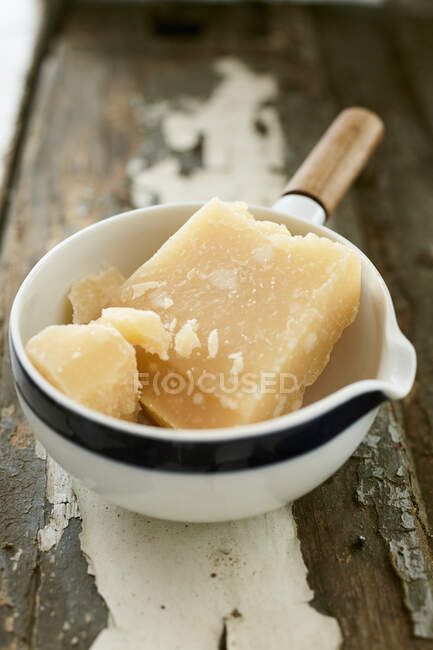 Parmesan in ceramic bowl with handle on rustic wooden surface — Stock Photo