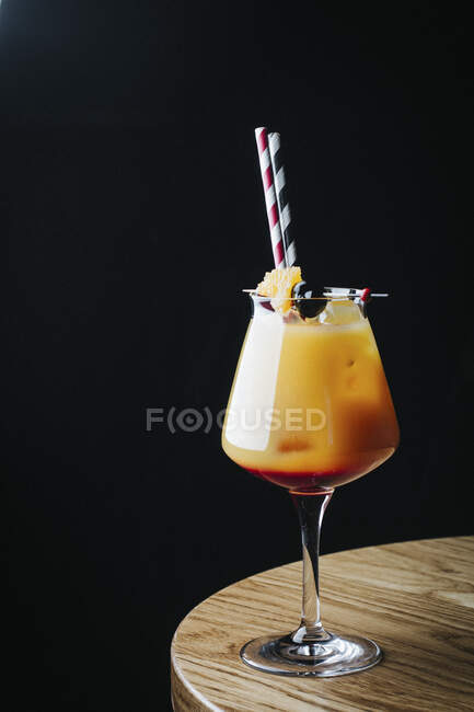 Orange cocktail with fruit and straws in elegant glass — Stock Photo