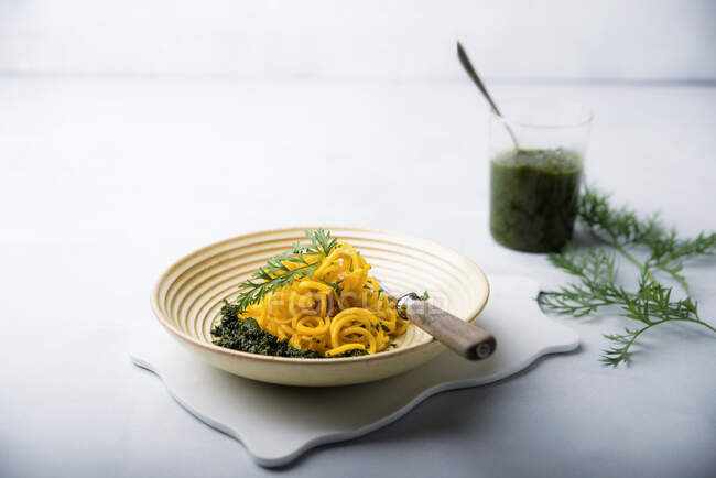 Gelbe Karottenspiralen mit veganem Pesto aus Karottenblättern — Stockfoto