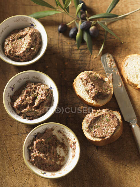 Tapenade in bowls and on slices of baguette — Stock Photo