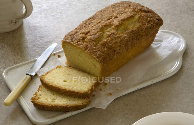 Lemon drizzle cake sliced with knife - foto de stock