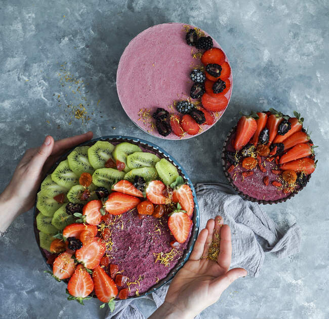 Vegan raw cheesecakes, top view with blueberry, cherry, matcha tea, orange, cashew cream, coconut butter and coconut milk, and base made of almonds, dates and dried apricots — Stock Photo