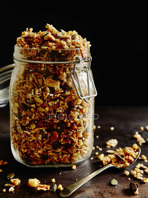 Homemade Granola in jar and on wooden surface with spoon — Stock Photo