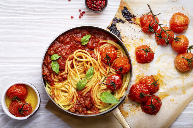 Close-up of pasta spaghetti with meat and tomato bolognese sauce in a pan served with basil and cherry tomatoes — Stock Photo