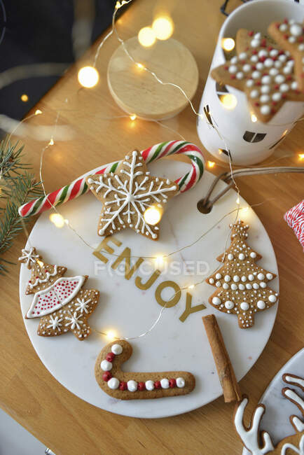 Pães de gengibre decorados em uma bandeja de mármore e pirulito de Natal — Fotografia de Stock