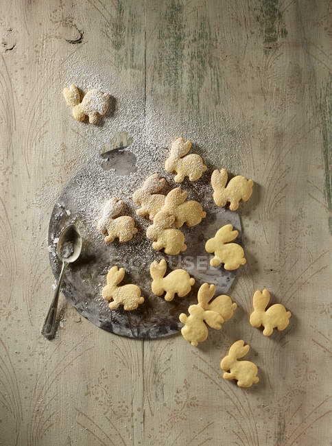 Rabbit shaped biscuits with icing sugar on a baking tray — Stock Photo