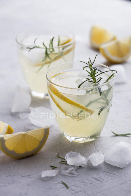 Lemonade with lemons and rosemary in glasses on table — Stock Photo
