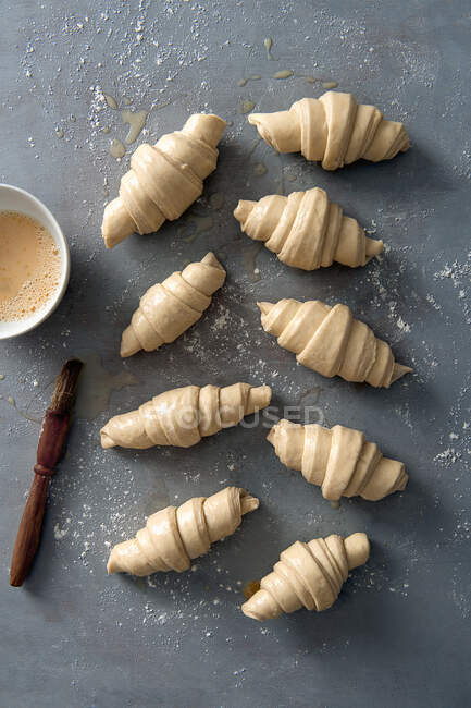 Homemade croissant glazed with eggwash, ready to be baked — Stock Photo
