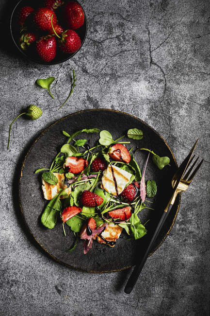Salad with halloumi strawberries arugula radish leaves and balsamic sauce — Stock Photo