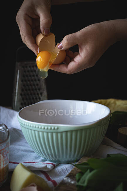 Mãos de mulher fazendo massa com farinha em um fundo preto — Fotografia de Stock