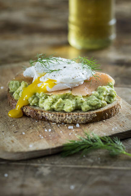 Bread topped with avocado cream, salmon and a poached egg — Fotografia de Stock