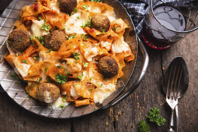 Gratinated tagliatelle with chickpea balls, tomato sauce and almond cheese — Stock Photo