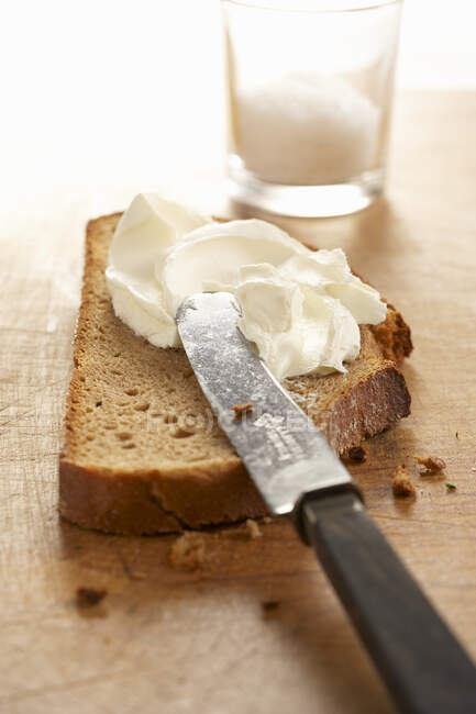 Pan de granja con queso crema y cuchillo - foto de stock
