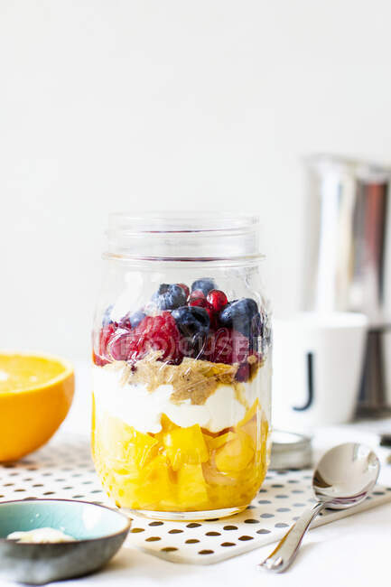 Layered dessert with fruit, cream, peanut butter and berries in jar — Stock Photo