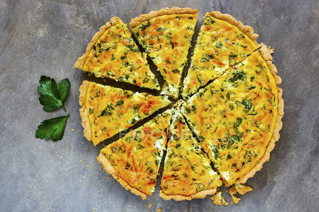 Cheese quiche with fresh herbs cut in pieces — Stock Photo