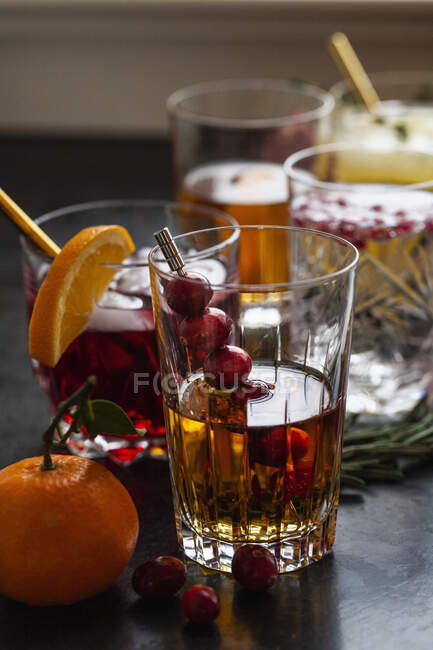 Várias bebidas alcoólicas com uísque, bourbon, vodka, cranberry, laranjas, romãs, alecrim e tomilho — Fotografia de Stock