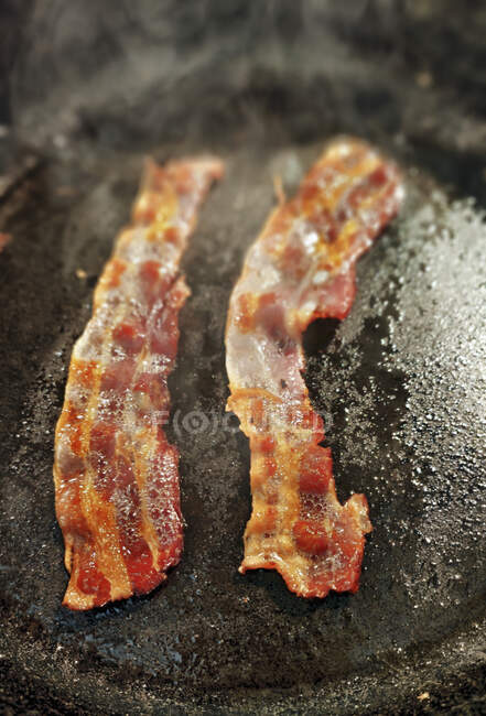 Roasted Bacon slices on pan sauce — Stock Photo