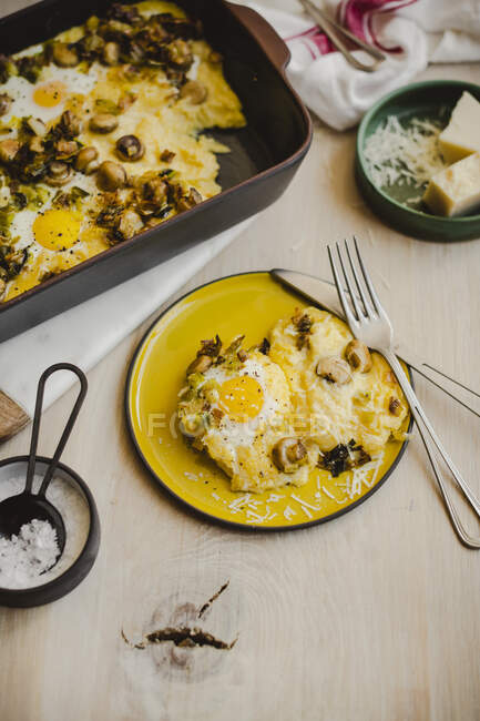 Polenta breakfast bake with eggs in tin and on plate — Stock Photo